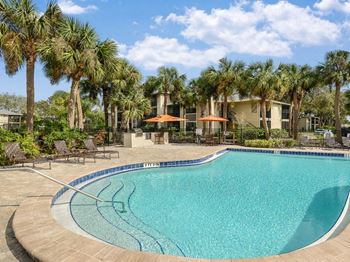 A swimming pool with palm trees in front of a building